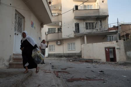 A woman walks past by an apartment building which was damaged by a rocket fired from Syria, in Nusaybin