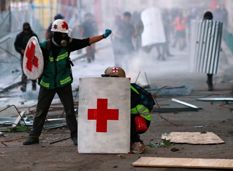 Personal médico se protegen con un escudo improvisado durante las protestas contra el gobierno en Chile