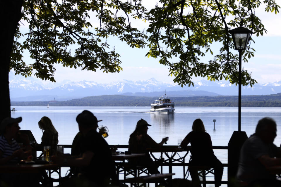 People enjoy the sunny weather and drink beer on the re-opening day of beer gardens, following the lifting of measures to avoid the spread of the corona virus, at lake 'Ammersee' in front of the alps in Inning, Germany, Monday, May 10, 2021. (AP Photo/Matthias Schrader)