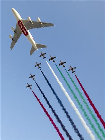 An Emirates A380 airliner, tailed by the Al Fursan Aerobatics team, flies over the Dubai Airshow November 18, 2013. REUTERS/Caren Firouz