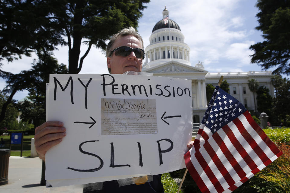 Dru Vincent and about a dozen other protesters, calling for the end of Gov Gavin Newsom's stay-at-home orders, demonstrated at the state Capitol in Sacramento, Calif., Wednesday, April 22, 2020. The California Highway Patrol announced Wednesday, that it is temporarily banning rallies at the state Capitol and other state facilities due to the pandemic. The change came after hundreds of protestors gathered on the Capitol grounds Monday, many without masks or following recommendations to remain six feet apart to slow the spread of the coronavirus. (AP Photo/Rich Pedroncelli)