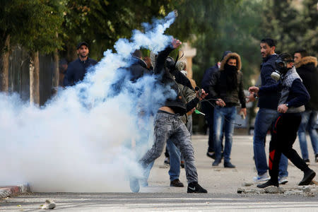 A Palestinian protester hurls back a tear gas canister fired by Israeli troops during clashes at a protest against U.S. President Donald Trump's decision to recognize Jerusalem as the capital of Israel, in the West Bank city of Bethlehem December 7, 2017. REUTERS/Mussa Qawasma