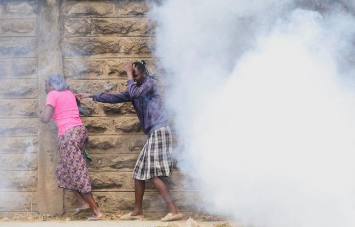 Women in the Mathare settlement in Nairobi, Kenya, try to run away from tear gas fired by police.