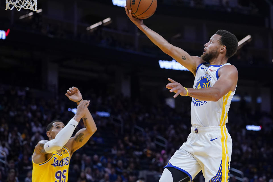 Golden State Warriors guard Stephen Curry, right, shoots a layup against the Los Angeles Lakers during the first half of a basketball game in San Francisco, Sunday, Oct. 9, 2022. (AP Photo/Godofredo A. Vásquez)