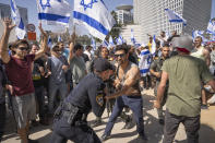 Israeli police officer scuffle with protesters as they try to block a main road to protest against plans by Prime Minister Benjamin Netanyahu's new government to overhaul the judicial system, in Tel Aviv, Israel, Wednesday, March 1, 2023. (AP Photo/Oded Balilty)