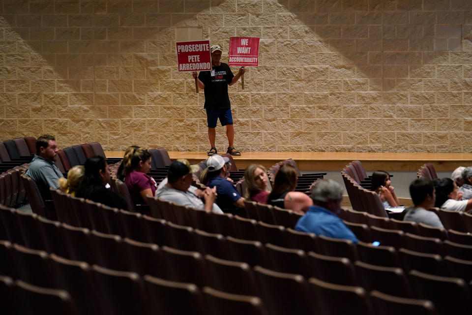 Michael Brown holds protest signs during a special school board meeting in Uvalde to address concerns over last month's shootings at Robb Elementary School, on July 18.<span class="copyright">Eric Gay—AP</span>