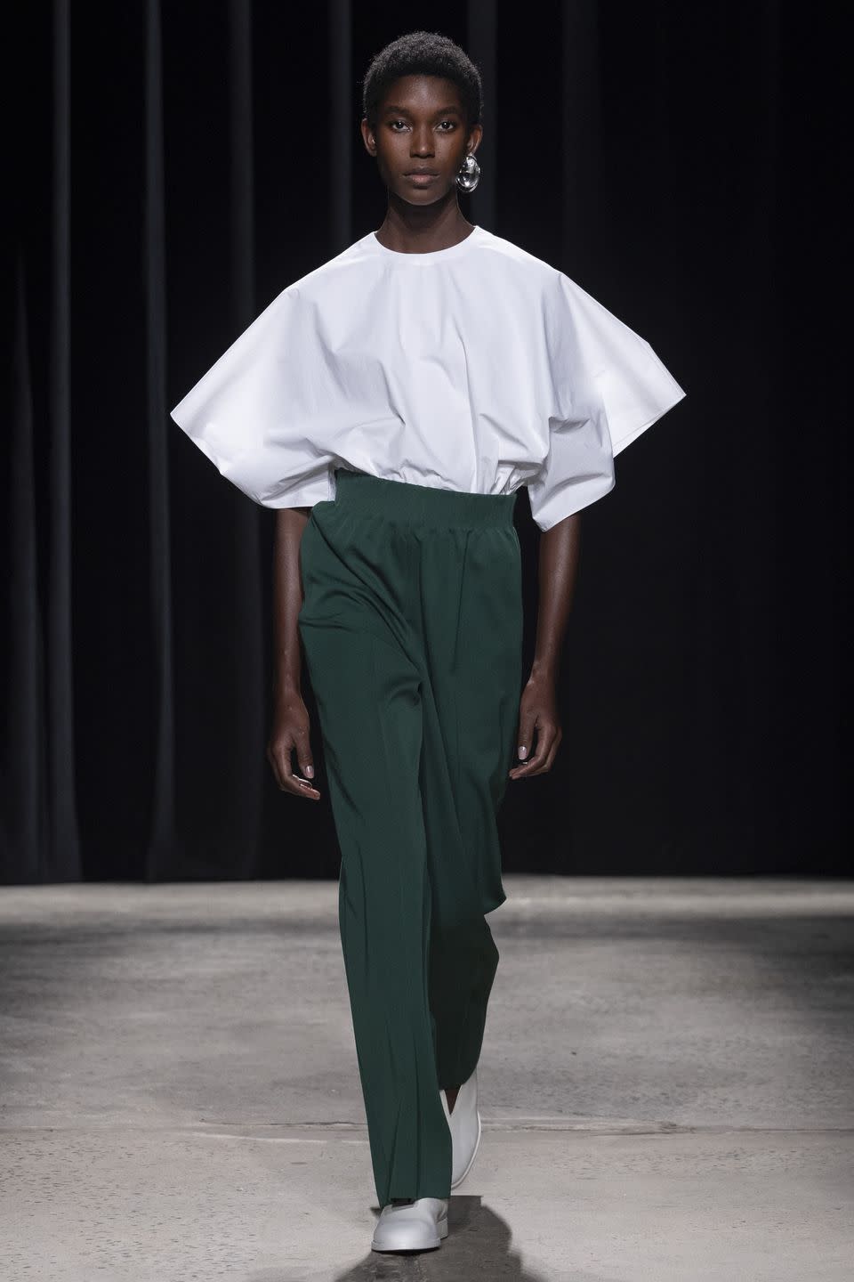a model wearing a white shirt and green pants