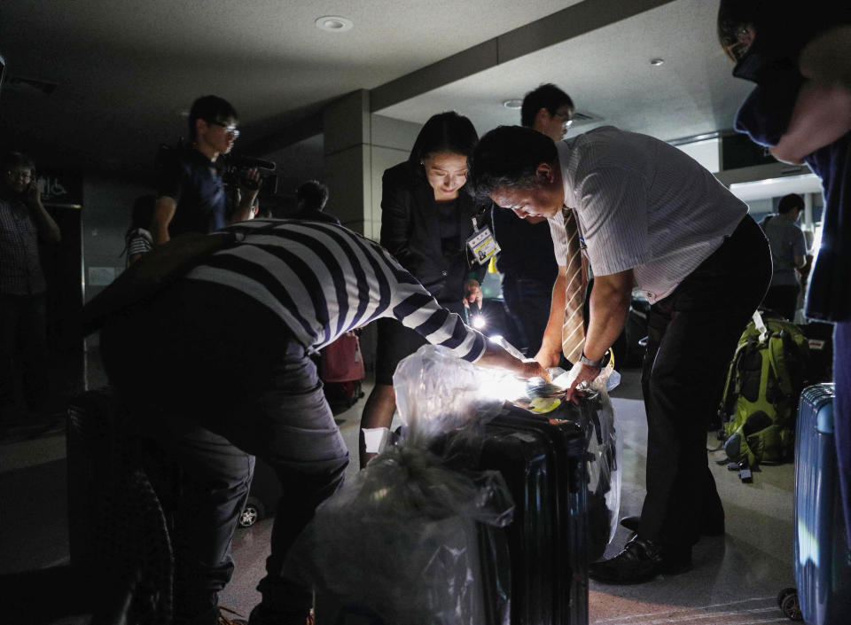 People use flashlights to check passengers' luggage at a terminal of Asahikawa airport in Asahikawa, Hokkaido, northern Japan during a black out following a strong earthquake Thursday, Sept. 6, 2018. A powerful earthquake rocked Japan's northernmost main island of Hokkaido early Thursday, triggering landslides that crushed homes, knocking out power and forcing a nuclear power plant to switch to a backup generator. (Kyodo News via AP)