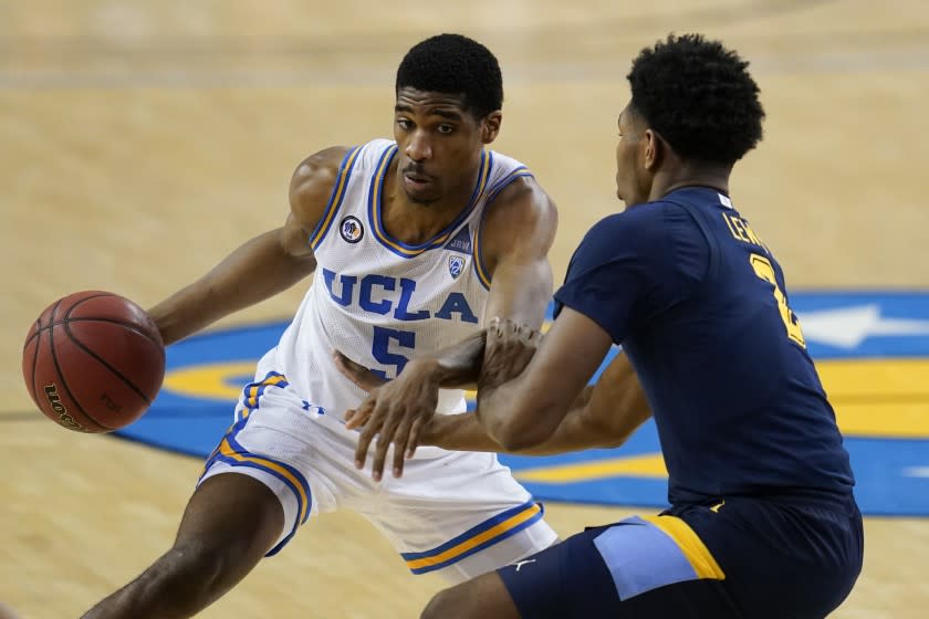 UCLA guard Chris Smith, left, is defended by Marquette forward Justin Lewis during the second half of an NCAA college basketball game Friday, Dec. 11, 2020, in Los Angeles. (AP Photo/Ashley Landis)