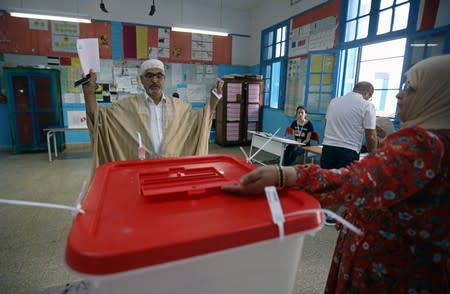 Man gestures as he casts his vote in a polling station during presidential election in Tunis