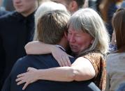 People hug along a street after the funeral of Josh Hunter in Calgary, Alberta April 21, 2014. Matthew de Grood has been charged with killing Hunter and four of his friends at a house party in Calgary's worst mass murder in the history of the city, according to local media reports. REUTERS/Todd Korol (CANADA - Tags: CRIME LAW OBITUARY)