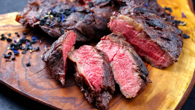 cooked and sliced oyster steak on wooden board