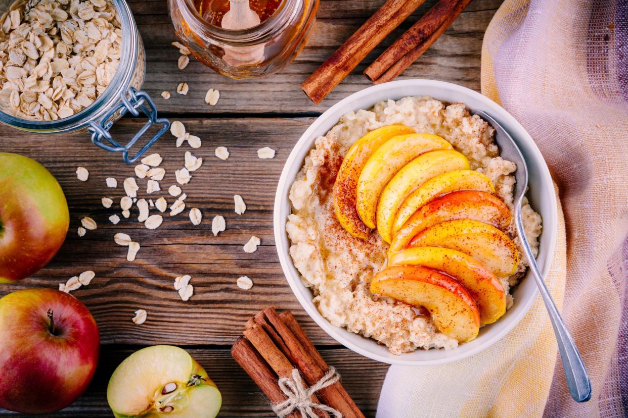 Healthy breakfast: oatmeal bowl with caramelized apples, cinnamon and honey on wooden background