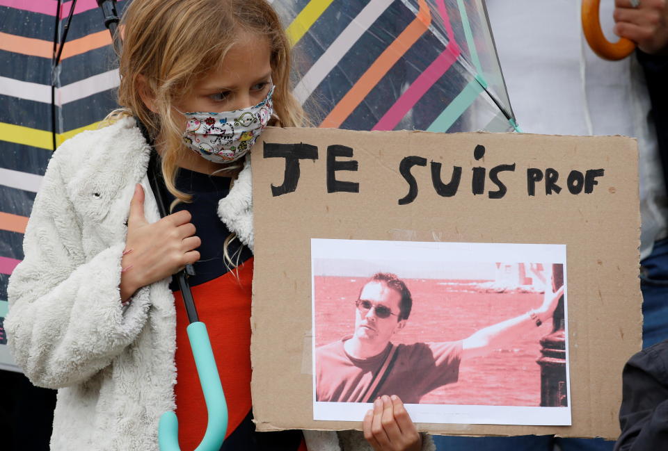 A girl holds a banner with a picture of Samuel Paty, the French teacher who was beheaded on the streets of the Paris suburb of Conflans St Honorine, during a tribute at the Place de la Republique, in Lille, France, October 18, 2020. / Credit: PASCAL ROSSIGNOL / REUTERS