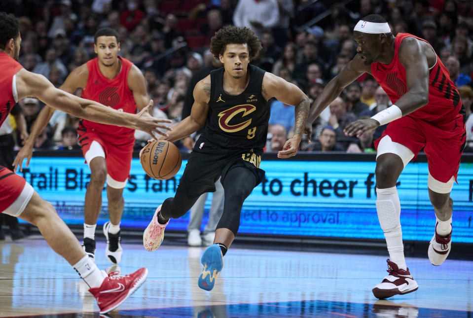 Cleveland Cavaliers guard Craig Porter, center, drives between Portland Trail Blazers center Duop Reath, right, and guard Skylar Mays during the first half of an NBA basketball game in Portland, Ore., Wednesday, Nov. 15, 2023. (AP Photo/Craig Mitchelldyer)