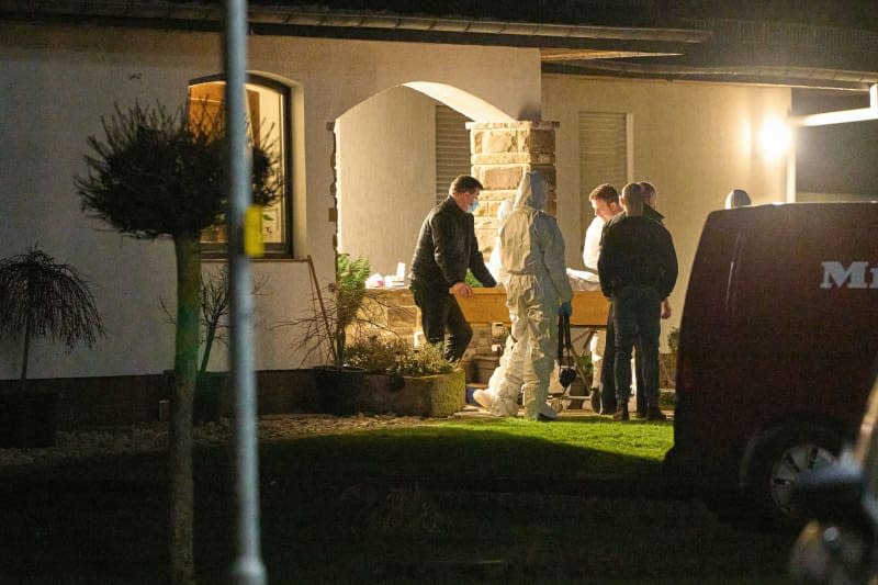 Investigators from the criminal investigation department and forensics remove a coffin from the crime scene following the violent attack in Montabaur in which several family members were killed. Thomas Frey/dpa