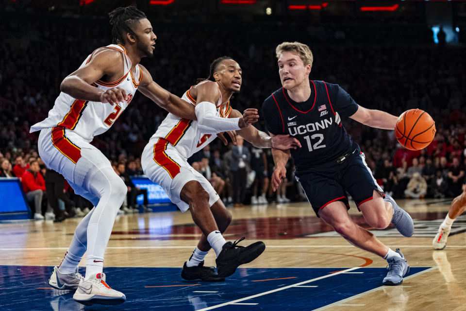 UConn guard Cam Spencer (12) drives to the basket against St. John's forward Sadiku Ibine Ayo (2) and guard Daniss Jenkins (5) during the first half of an NCAA college basketball game on Saturday, Feb. 3, 2024, in New York. (AP Photo/Peter K. Afriyie)