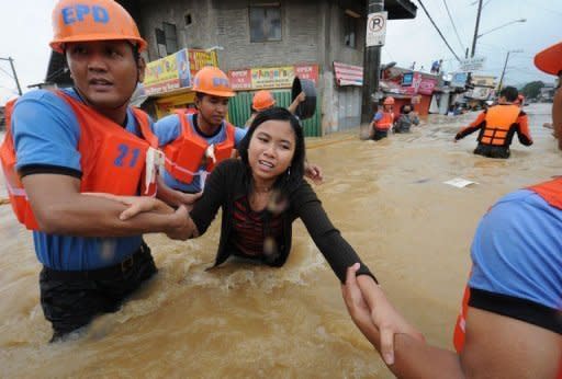 Rescuers help a woman cross a flooded street as residents are evacuated from their homes in the village of Tumana, Marikina town, in suburban Manila. Torrential monsoon rains flooded half of the Philippine capital on Tuesday, killing at least 16 people as rampaging waters swept away homes, destroyed bridges and triggered a landslide in a shanty town