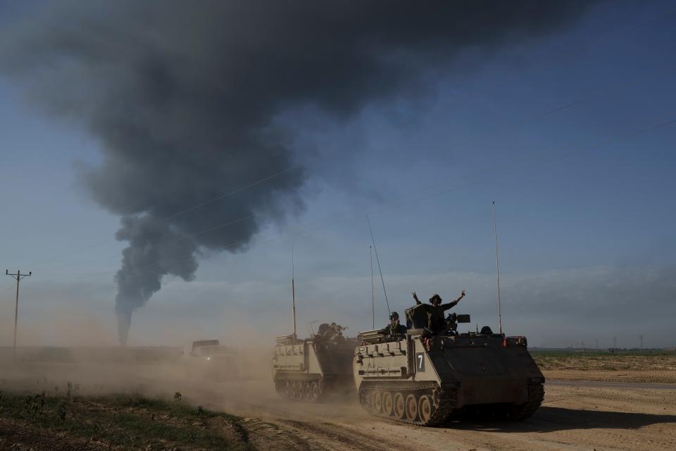 Israeli soldiers move on armored personnel carriers near the Israeli-Gaza border as smoke rises into the sky in the Gaza Strip on Jan. 21, 2024.