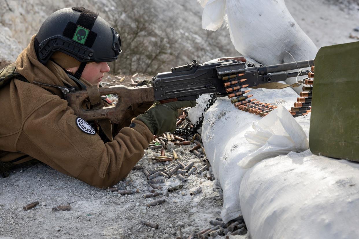 ukrainian soldier with a helmet on holds gun lying on stomach in snow