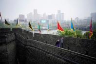 People wearing face masks walk on an ancient city wall in Jingzhou, after the lockdown was eased in Hubei