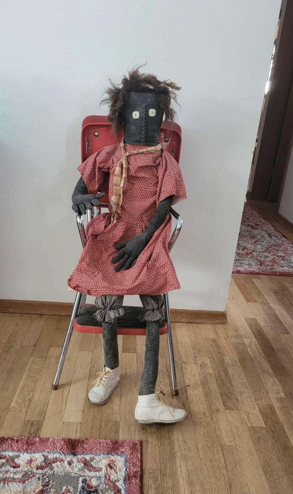 creepy doll wearing clothes and shoes sitting on a chair