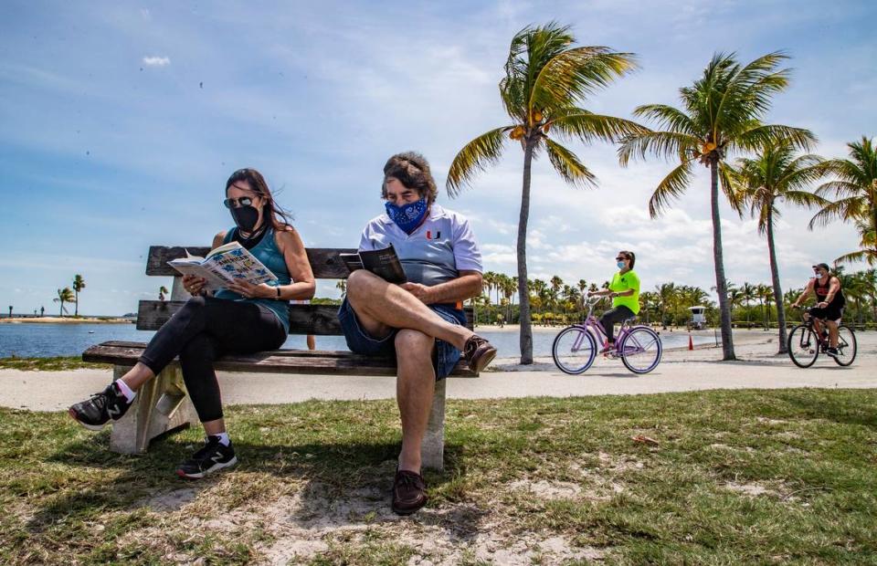 Barbara y Gary Keisberg tomándose un tiempo para leer sus libros mientras visitan Matheson Hammock Park durante una visita en 2020.