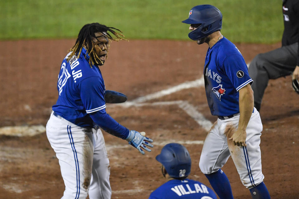 Toronto Blue Jays' Vladimir Guerrero Jr., left, and Randal Grichuk, right, celebrate after scoring against the New York Yankees on a double by Alejandro Kirk during the sixth inning of a baseball game in Buffalo, N.Y., Thursday, Sept. 24, 2020. (AP Photo/Adrian Kraus)