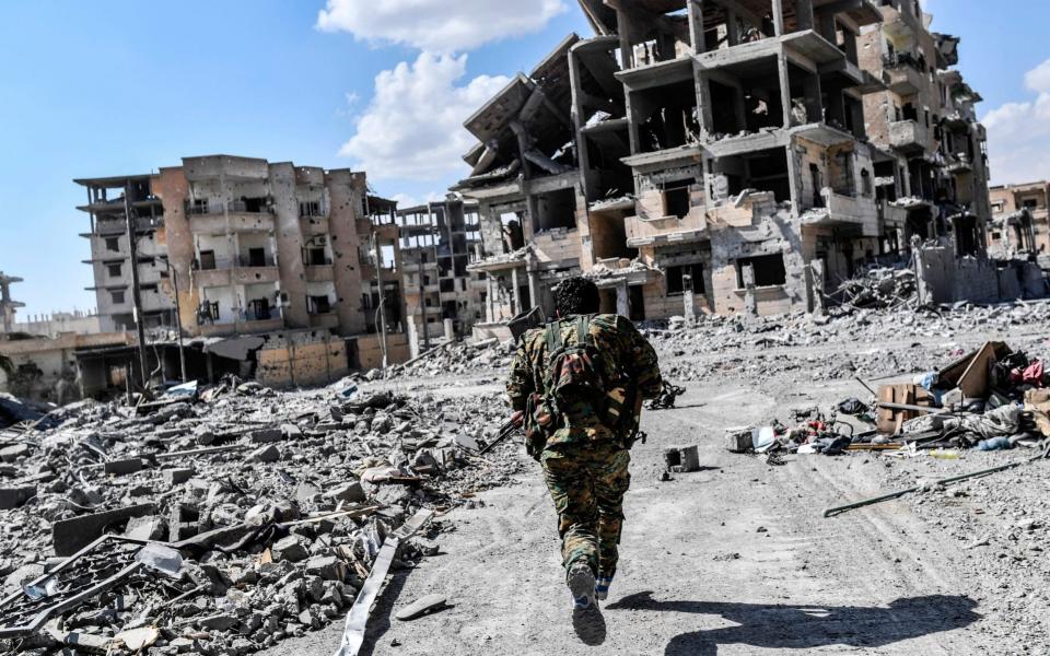 A member of the Syrian Defence Forces runs for cover in the battle for Raqqa - AFP