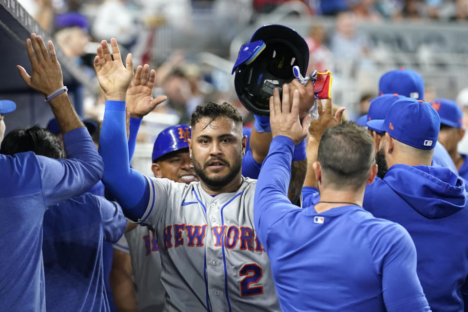 New York Mets' Omar Narvaez (2) is congratulated after scoring on a double by Brandon Nimmo during the seventh inning of the team's opening-day baseball game against the Miami Marlins, Thursday, March 30, 2023, in Miami. (AP Photo/Lynne Sladky)