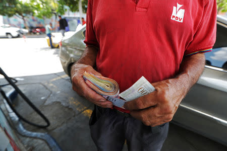 A worker holds a wad of Venezuelan bolivar notes at a state oil company PDVSA's gas station in Caracas, Venezuela May 17, 2019. REUTERS/Ivan Alvarado