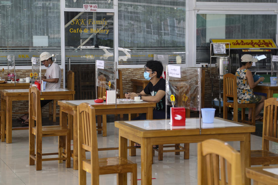 Customers sit behind plastic sheet to help curb the spread of the new coronavirus at a tea-shop in Yangon, Myanmar Monday, May 18, 2020. (AP Photo/Thein Zaw)