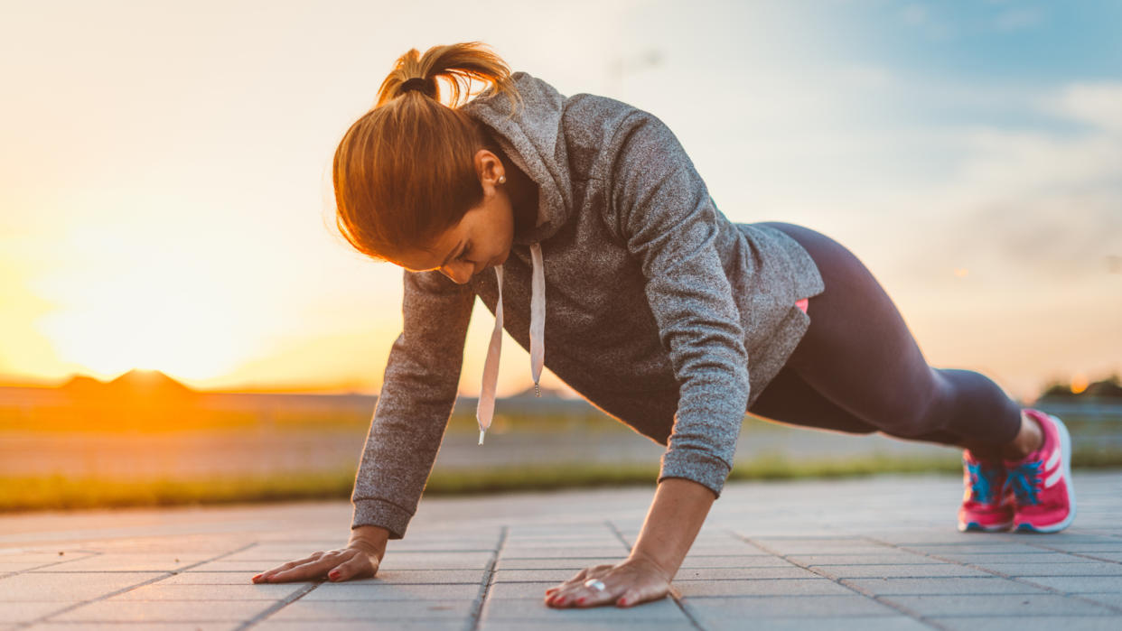  A woman performing a push-up outside. 