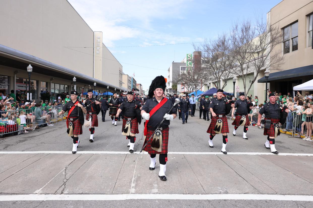 A pipe and drum band moves along Broughton Street during the Savannah St. Patrick's Day Parade on Saturday, March 16, 2024.