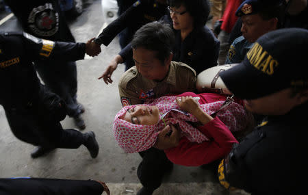 Government security officials carry a family member of passengers onboard missing AirAsia flight QZ8501 after she collapsed at a waiting area in Juanda International Airport, Surabaya, December 30, 2014. REUTERS/Beawiharta