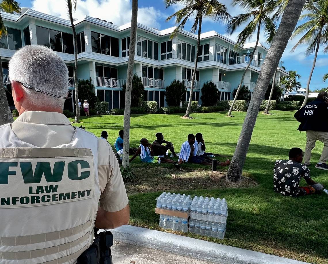 A Florida Fish and Wildlife Conservation Commission officer watches over migrants on the grounds of the Ocean Reef gated community in north Key Largo Saturday, Aug. 6, 2022.