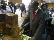Zimbabwe's President Robert Mugabe cuts his birthday cake as he marks his 93rd birthday at his offices in Harare, Tuesday, Feb. 21, 2017. Mugabe described his wife Grace, an increasingly political figure, as "fireworks" in an interview marking his 93rd birthday. (AP Photo/Tsvangirayi Mukwazhi)