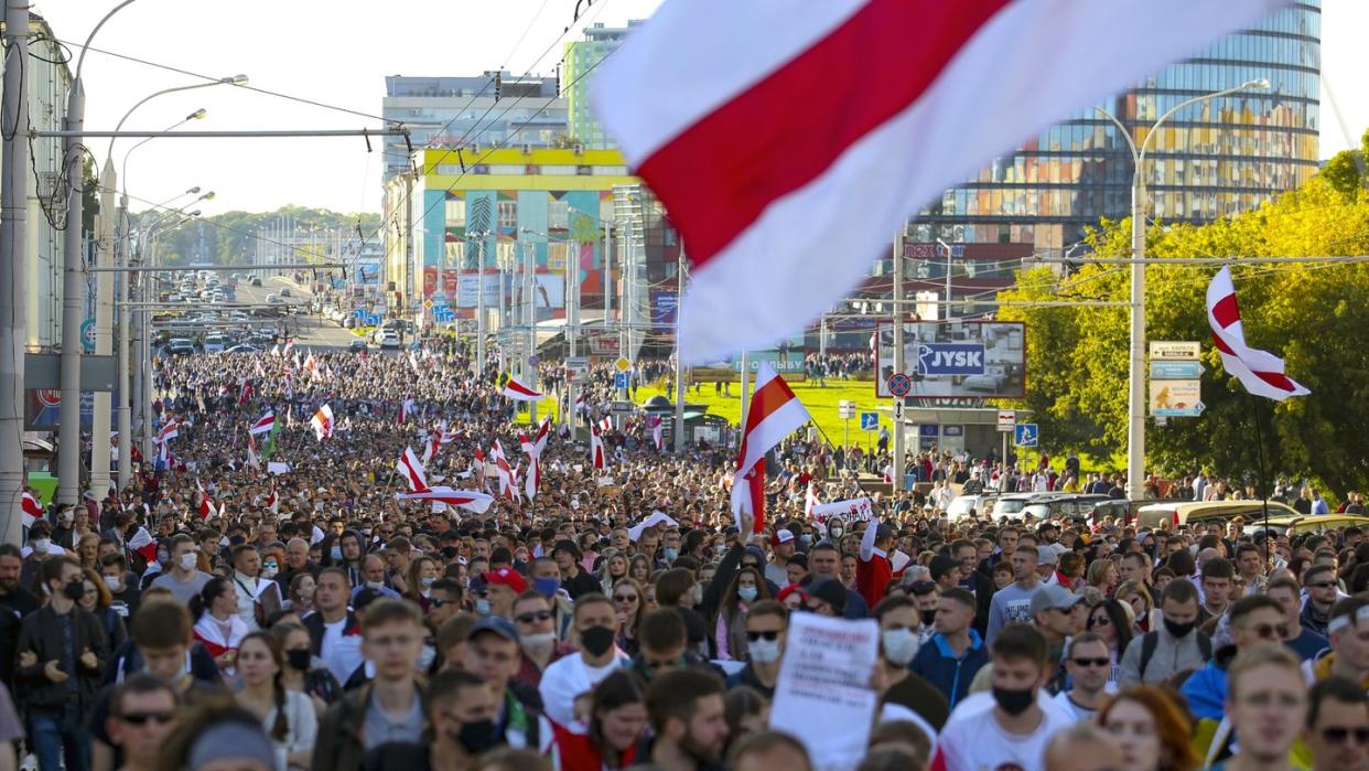 Demonstranten mit alten belarussischen Nationalflaggen gehen nach einer Kundgebung der Opposition durch Minsk, um gegen die offiziellen Ergebnisse der Präsidentschaftswahlen zu protestieren.