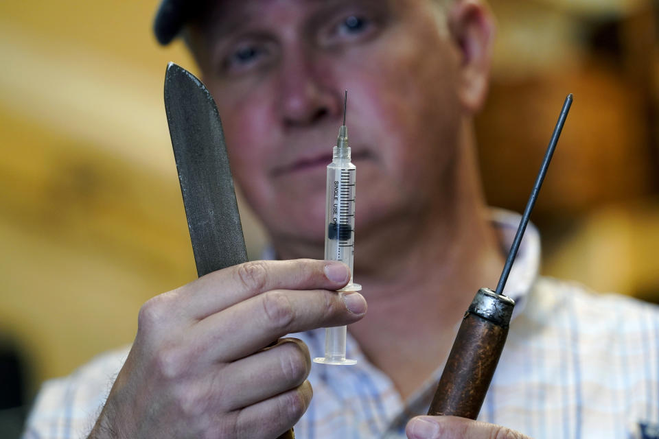 Movie prop master Scott Reeder displays retractable props at his shop in Austin, Texas, April 26, 2021. Reeder's TikTok video about prop retractable needles was used without his permission to spread false claims about politicians getting fake vaccinations. Individuals across the country, like Reeder, have found themselves swept into the misinformation maelstrom, their online posts or their very identities hijacked by anti-vaccine activists and others peddling lies about the COVID-19 outbreak. (AP Photo/Eric Gay)