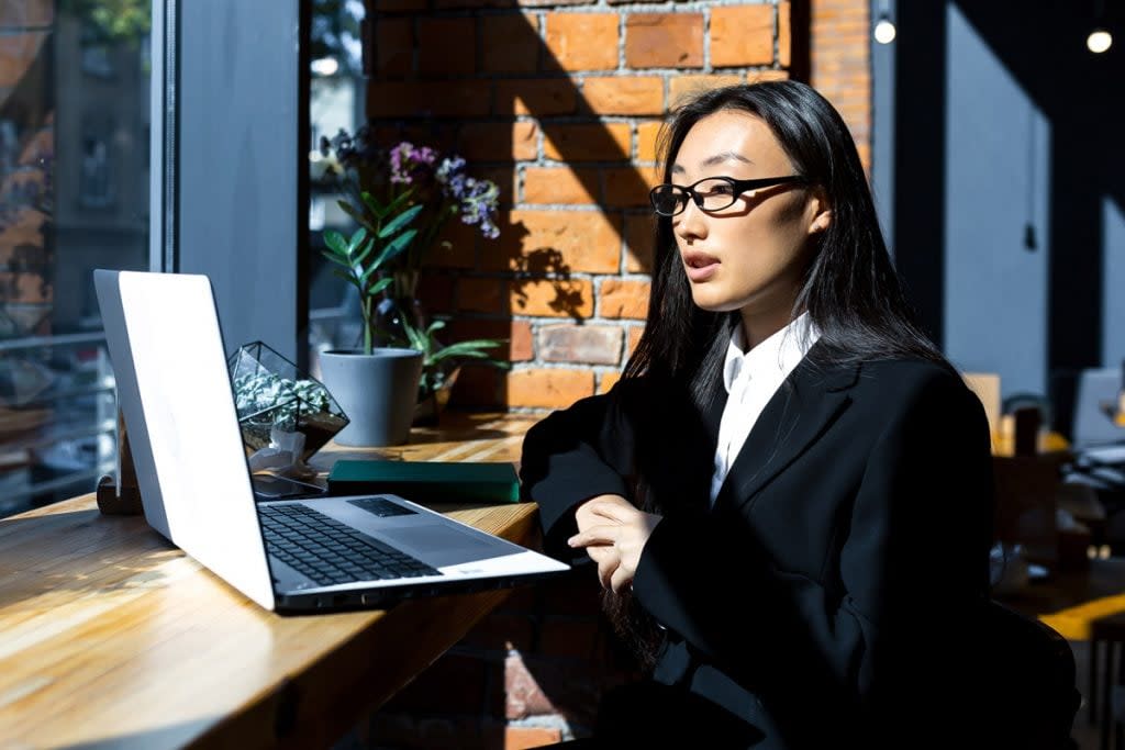 A woman works remotely from a coffee shop. 