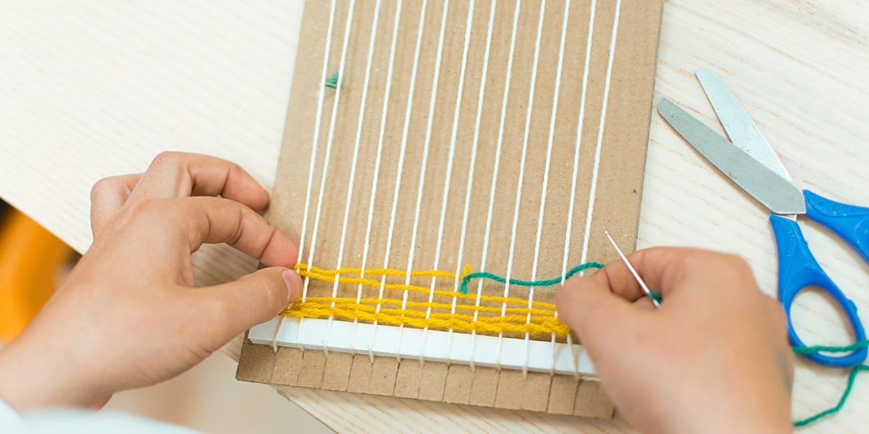 children's hands weaving a pot holder loom