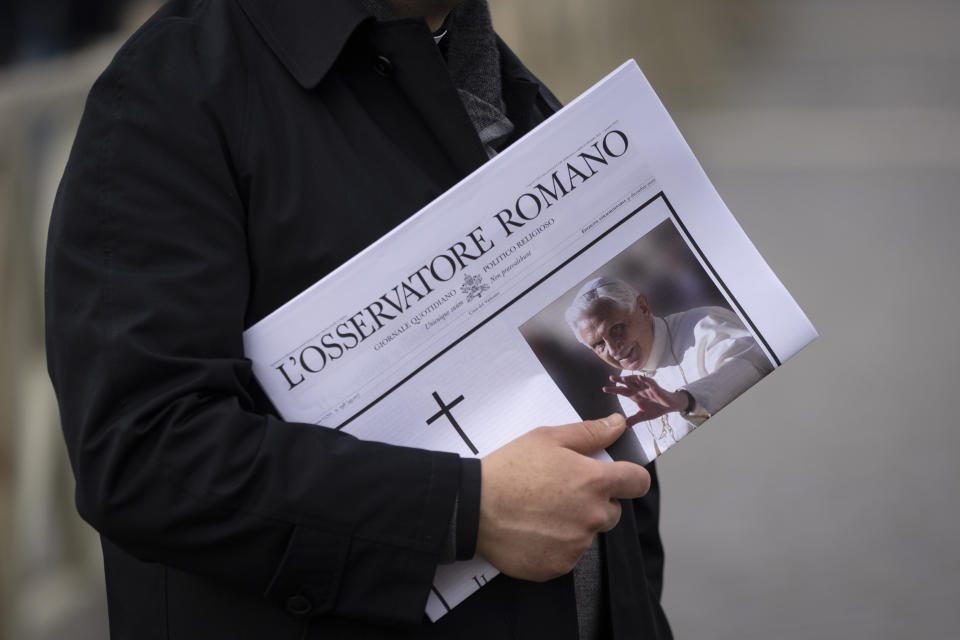 A man holds a copy of the Vatican newspaper as he waits to view the body of Pope Emeritus Benedict XVI as it lies in state in St. Peter's Basilica at the Vatican, Tuesday, Jan. 3, 2023. The Vatican announced that Pope Benedict died on Dec. 31, 2022, aged 95, and that his funeral will be held on Thursday, Jan. 5, 2023. (AP Photo/Ben Curtis)