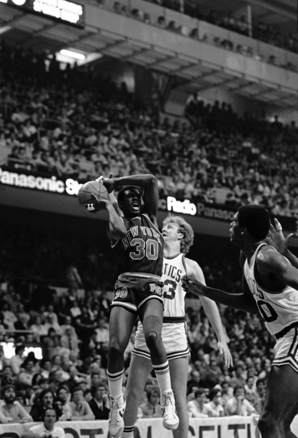 New York Knick Bernard King (30) reacts as Boston Celtics Larry Bird, center, gets a hand on the ball to block his shot during third period NBA playoff action at Boston Garden, Sunday, April 29, 1984, Boston, Mass. Boston beat New York 110-92. The player on the right is unidentified. AP Photo/Paul Benoit