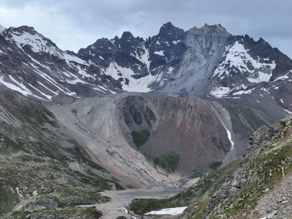 landscape picture showing a mountain after a huge landslide, with snow covering the peaks and deluge winding down the center