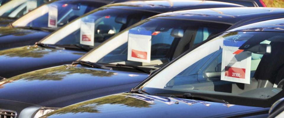 Cars for sale with signs hanging from rearview mirror