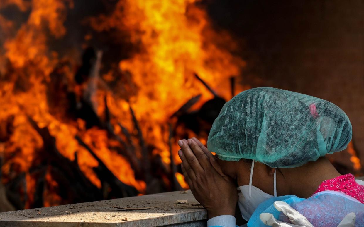 Relatives of a Covid victim mourn at a cremation ground in New Delhi, India - Shutterstock