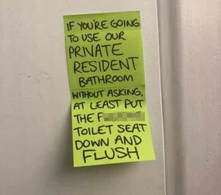 A yellow note on a bathroom door asking tradies to put the toilet seat down and flush. 