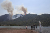 People watch a wildfire burning the forest in Turgut village, near tourist resort of Marmaris, Mugla, Turkey, Wednesday, Aug. 4, 2021. As Turkish fire crews pressed ahead Tuesday with their weeklong battle against blazes tearing through forests and villages on the country's southern coast, President Recep Tayyip Erdogan's government faced increased criticism over its apparent poor response and inadequate preparedness for large-scale wildfires.(AP Photo/Emre Tazegul)