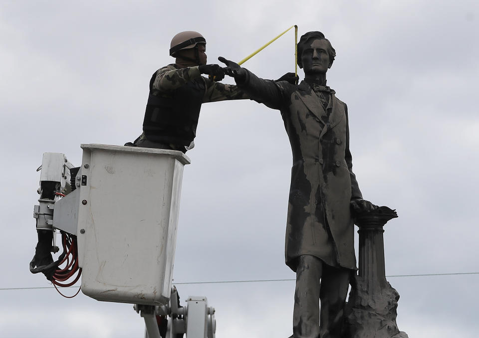 A New Orleans city worker wearing body armor and a face covering measures the Jefferson Davis monument on May 4 after a Louisiana House committee voted to advance a bill that would forbid the removal of Confederate monuments in the state. The city removed four Confederate monuments in April.&nbsp; (Photo: Justin Sullivan via Getty Images)