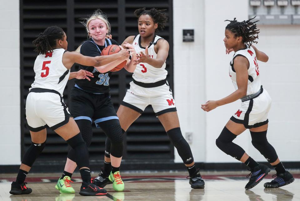 Mercy's Alyssa Murphy is pressured by DuPont Manual's Sydne Tolbert and DuPont Manual's Jakayla Thompson in the first half at DuPont Manual High School. Dec. 6, 2022